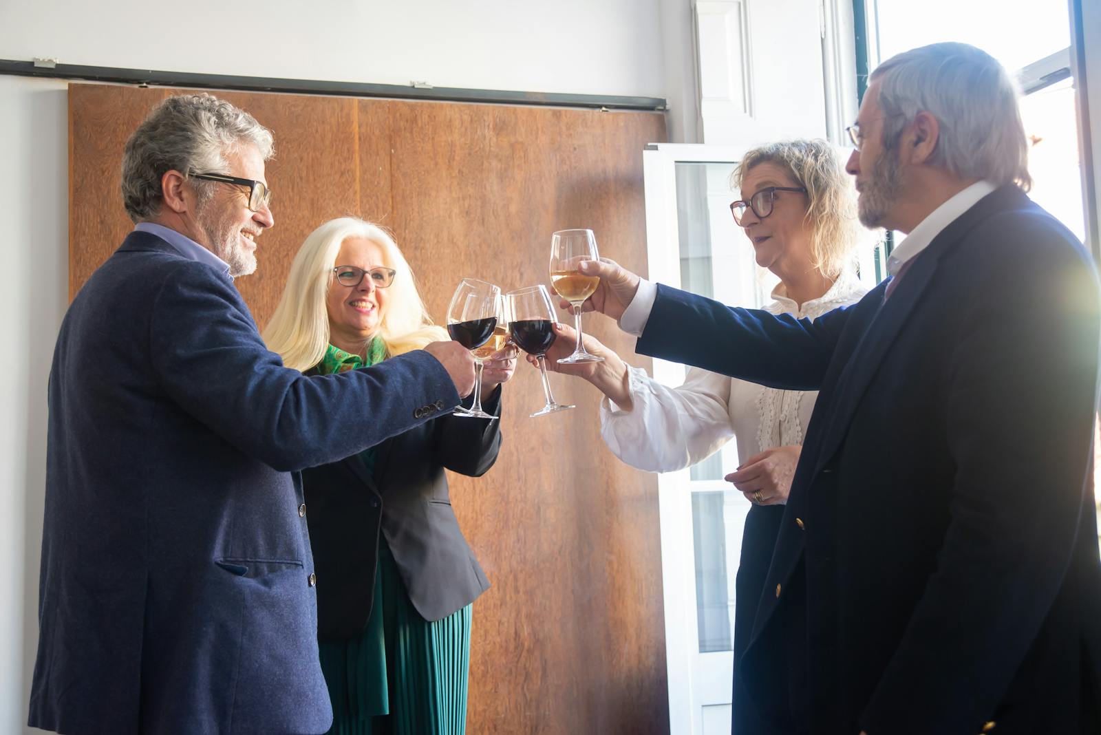Senior adults raise wine glasses in a celebration indoors in Portugal, capturing a joyful and elegant moment.