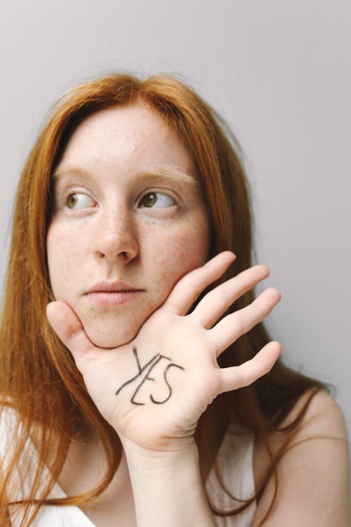 Portrait of a woman holding hand with 'Yes' written, conveying optimism.