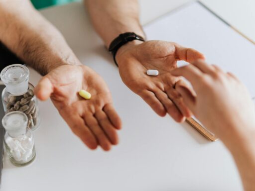 From above anonymous female and unrecognizable doctor man giving yellow and white tablets for choosing while working in modern clinic